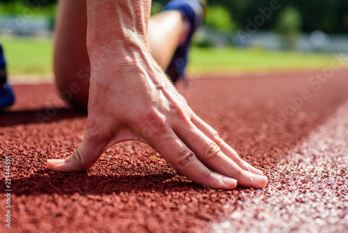 Hand of sportsman on running track low start position. Runner ready to go close up. Flexibility is ability to stretch joint to limit of range movement. Joint care for runners. Ultimate remedies