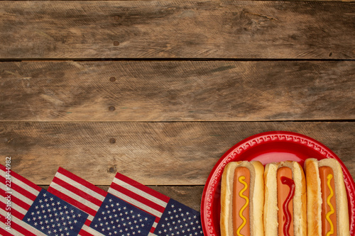 Three hot dogs on a red plate mustard ketchup background with copy space