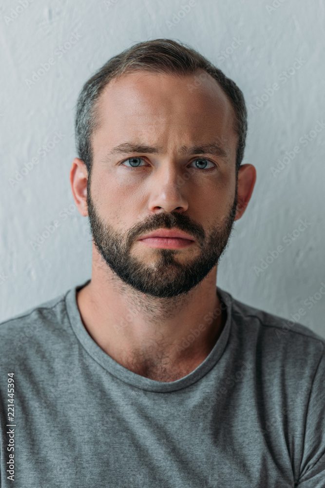 Fototapeta premium close-up portrait of frustrated bearded man looking at camera on grey