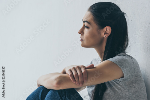 Canvastavla side view of beautiful frustrated brunette girl sitting and looking away on grey