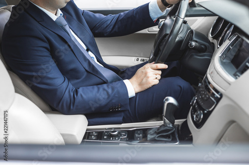 a businessman driving a prestigious car holds a mobile phone in his hand. Hasty life © xartproduction