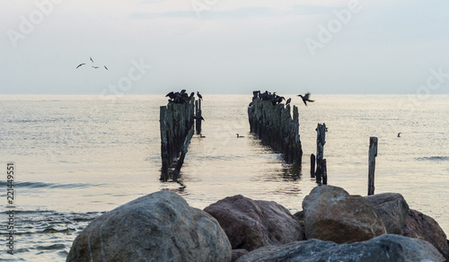 Old broken abandoned coastal pier in Baltic Sea, pier in focus, stone backgro...