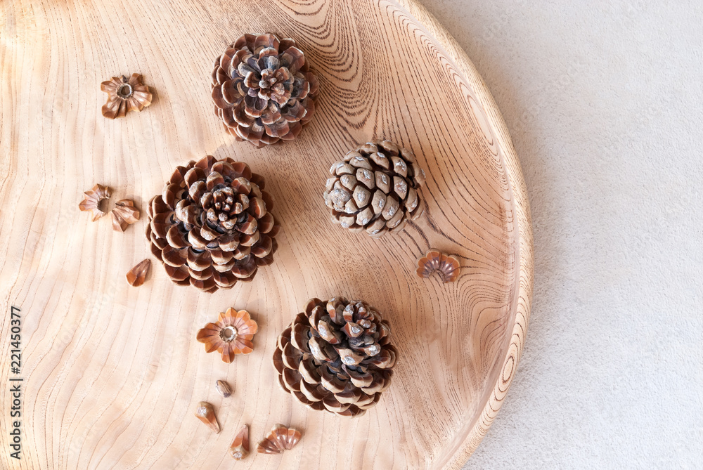 Fototapeta premium Opened ripe pine cones with nuts on wooden tray.
