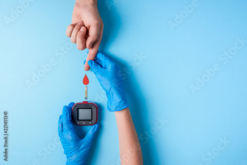 Nurse making a blood test. Man's hand with red blood drop with Blood glucose test strip and Glucose meter photo