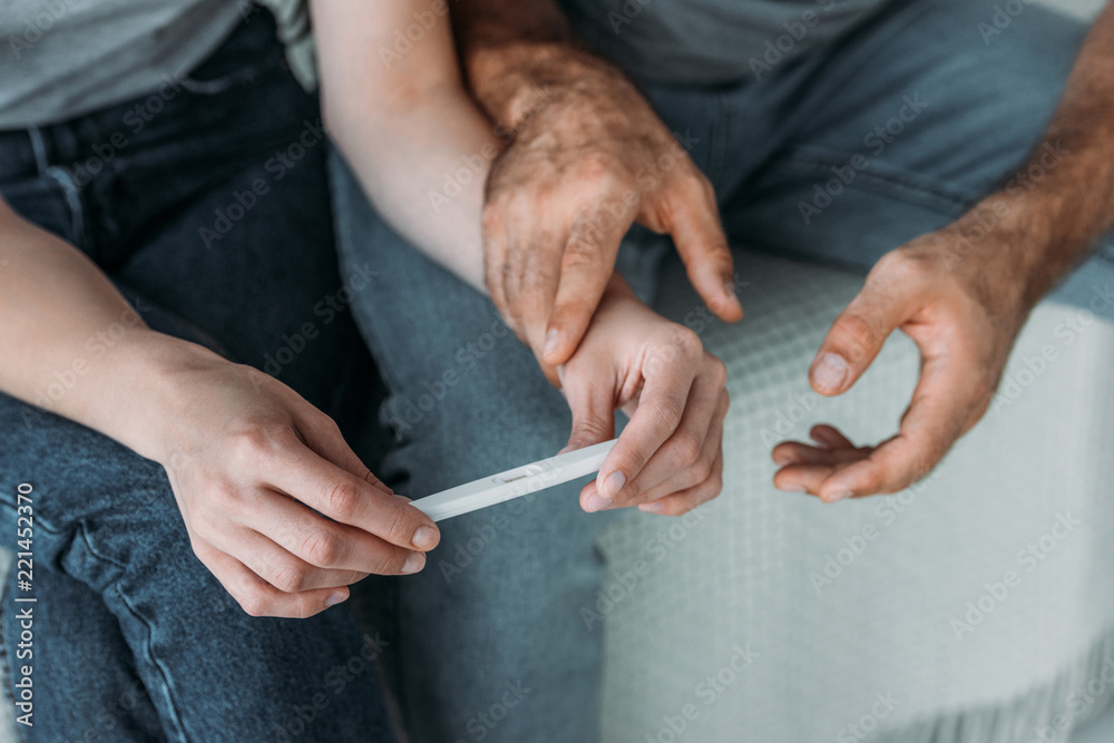 cropped shot of unhappy couple holding pregnancy test