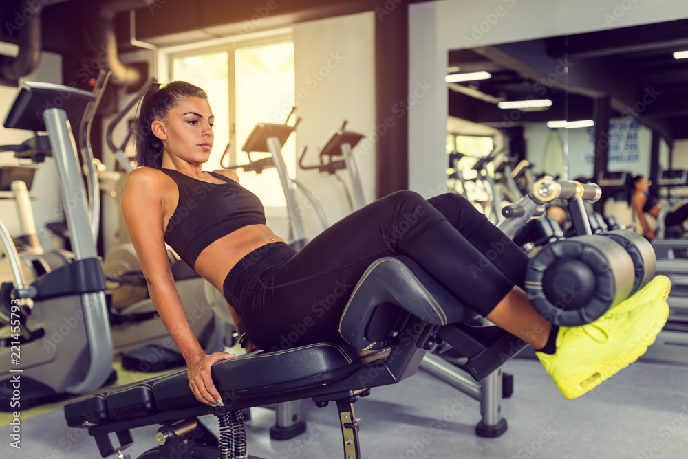 Attractive Young woman doing sit up exercise with machine at the gym.