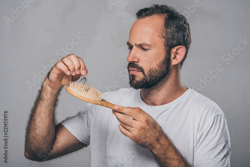 bearded middle aged man holding hairbrush, hair loss concept photo