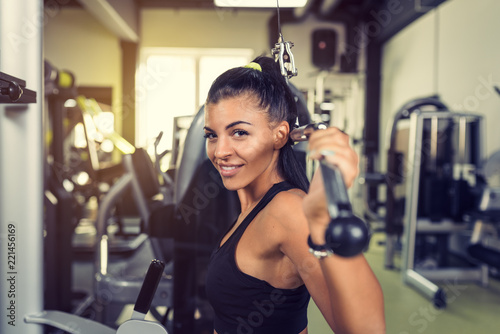 Woman using lat pulldown machine in gym fitness