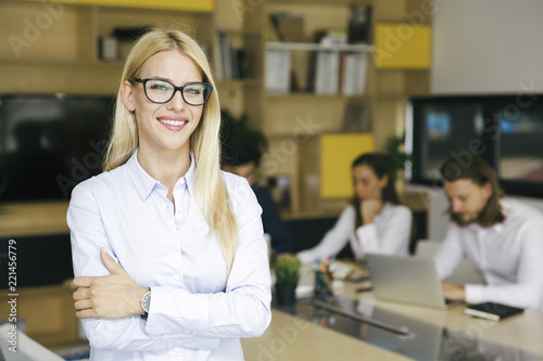 Tableau sur toile Young businesswoman standing in the office and other young business people worki