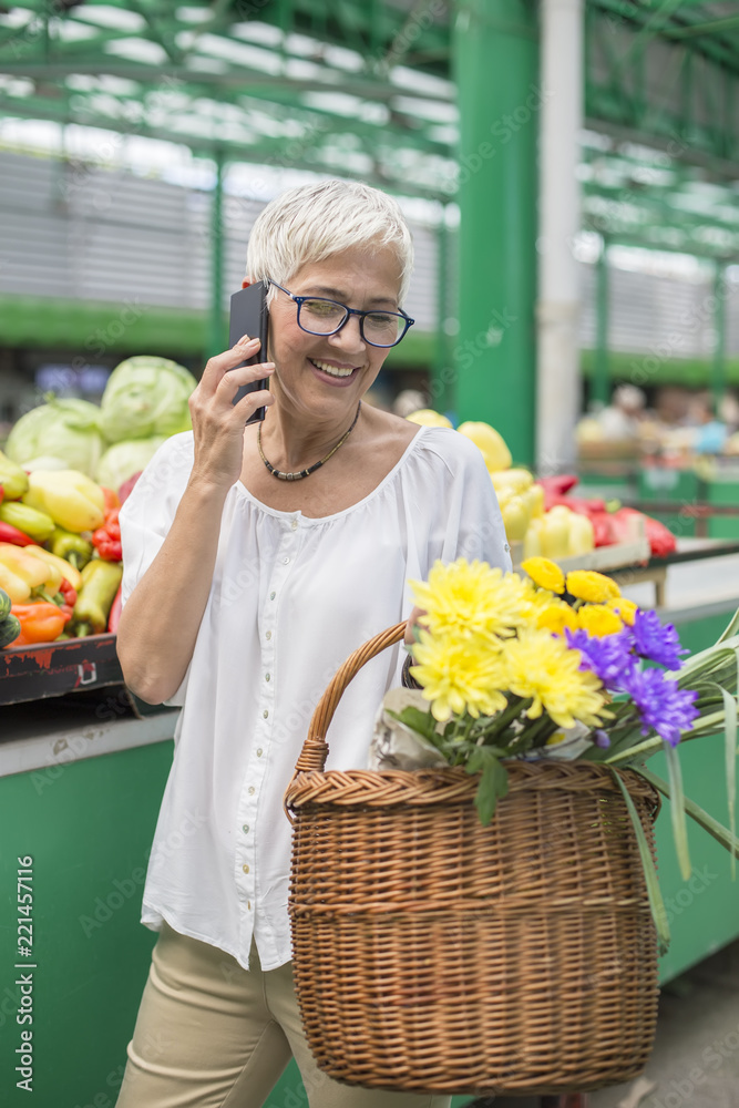 Senior woman on market using mobile phone
