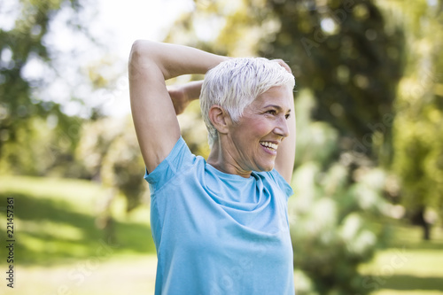 Photos Senior woman doing exercise for stretching hand in the park