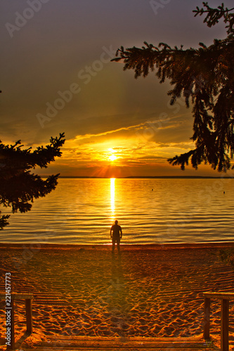 Stairs leading down to a beach with a man watching the sun setting over Waskesiu Lake in Prince Albert National Park of Canada. photo