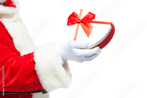 Christmas. Santa Claus in white gloves holds a white heart-shaped gift box with a red ribbon. Isolated on white background. Close up