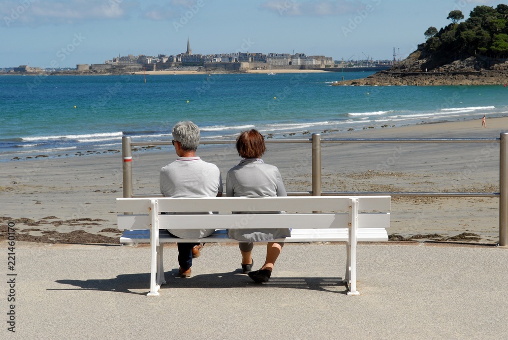 Couple assis sur un banc face à Saint-Malo 
