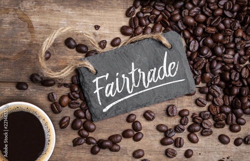 Fairtrade Kaffeetasse und Kaffeebohnen mit Kreidetafel auf Holzhintergrund