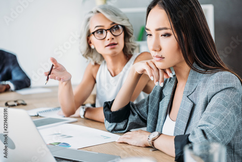 irritated businesswoman gesturing and talking to colleague in office photo