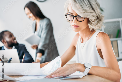 attractive young caucasian businesswoman reading documents in office