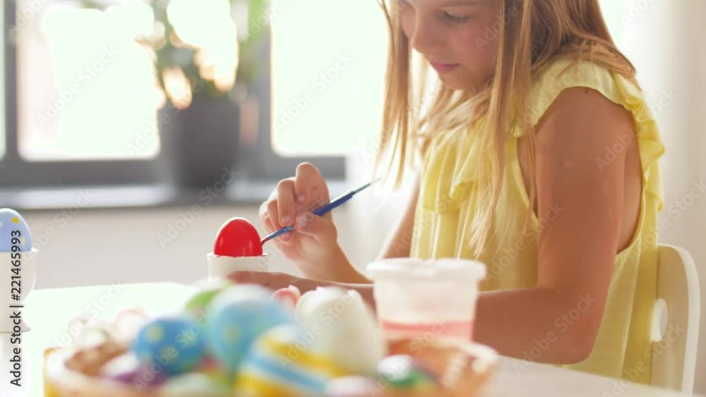 easter, holidays and people concept - happy girl coloring eggs with colors and brush at home easter, holidays and people concept - happy girl coloring eggs with colors and brush at home
