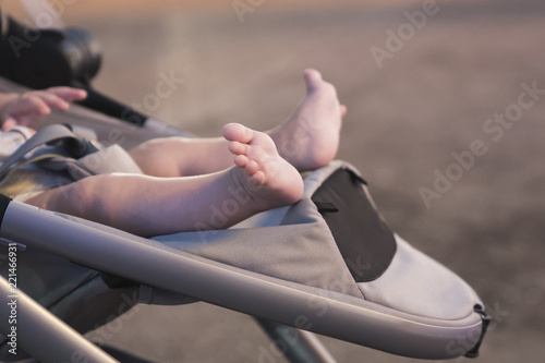 Newborn baby barefoot sleeping in stroller outdoors