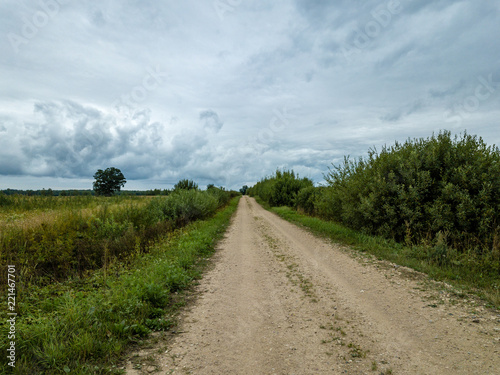 drone image. aerial view of rural gravel road in green forest and trees with shadows from above