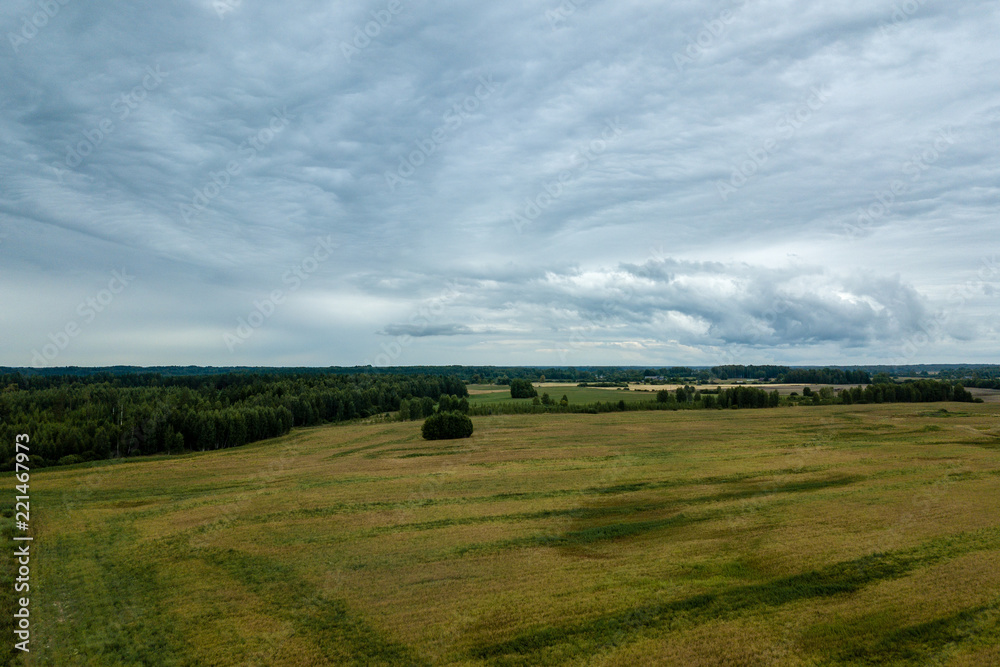 drone image. aerial view of rural area with fields and forests under dramatic storm clouds forming