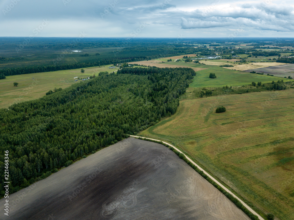 drone image. aerial view of rural area with fields and forests under dramatic storm clouds forming