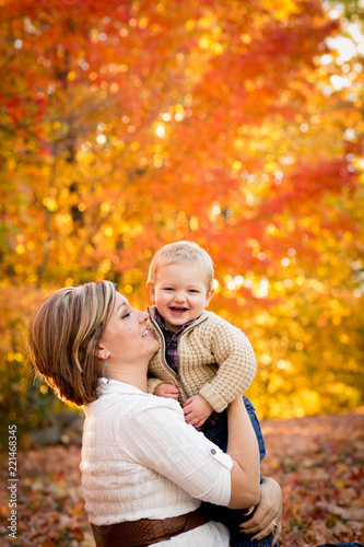 Happy Mother Holding Son in Autumn Park