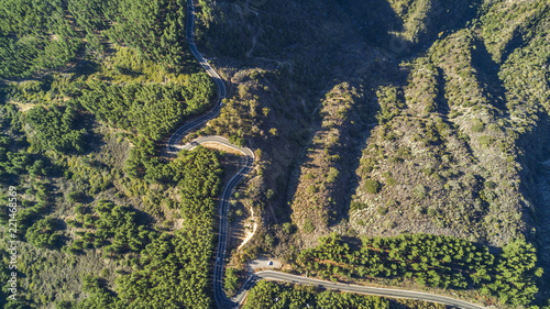 An aerial view from top with the drone of a road in Valparaiso Region, Chile, the road make bends around the forest in order to go down on the cliff to get to the beach, amazing the forest and curves 