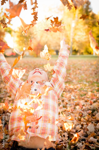 Little Boy Laughing and Throwing Autumn Leaves