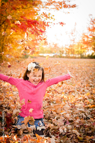 Happy Girl Laughing and Throwing Autumn Leaves
