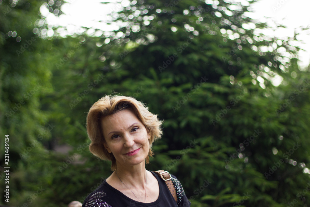 blond  woman  40 years old in park in black top