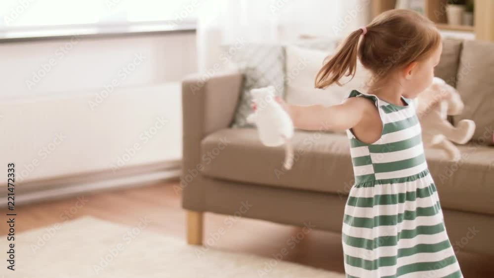 childhood and people concept - happy three years old baby girl playing and dancing with soft toy rabbit and mouse at home
