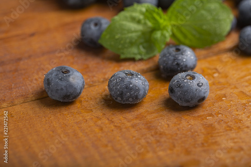 Juicy and fresh blueberries with green mint leaves on a wooden table. Blueberries on wooden background.