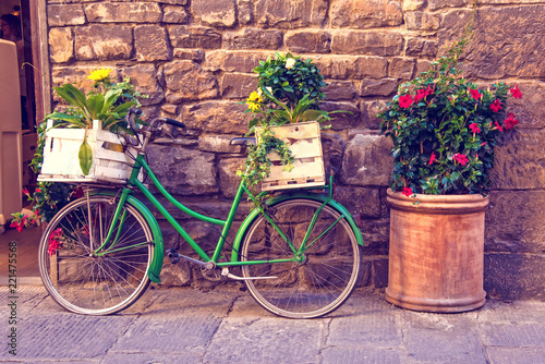 Beautiful city landscape with a green bike near the old wall with flowers in drawers in Florence, Italy, Europe.