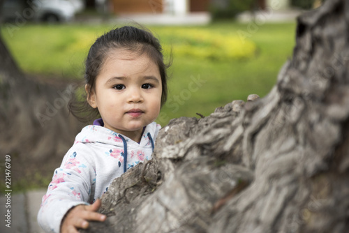 Little girl hugging a tree, looking up