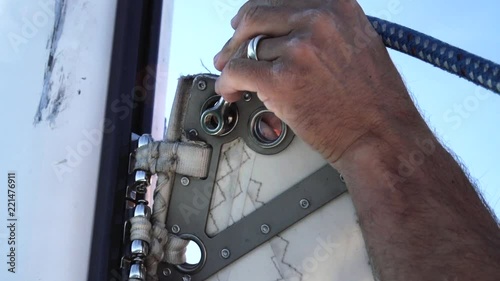 Crew hands attaching halyard to top of main sheet