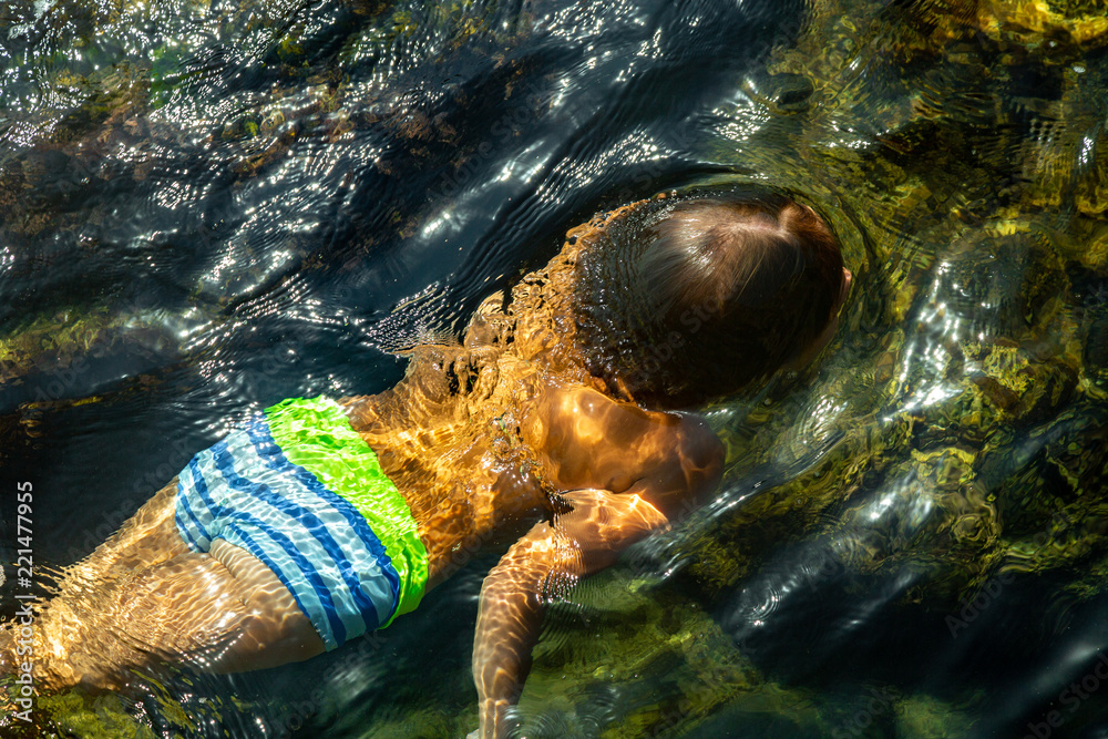 Boy swimming underwater, beautiful view of crystal clear transparent water of sea Boy swimming underwater, beautiful view of crystal clear transparent water of sea