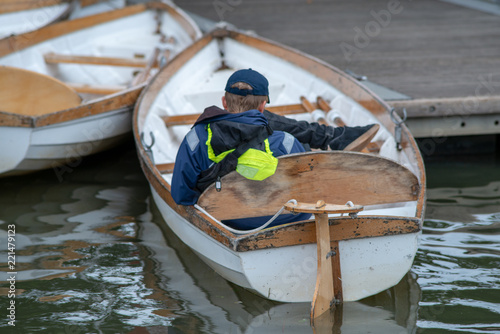 Slika na platnu boy in blue cap and coat lazing in white rowing boat during the English autumn