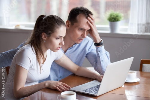 Upset millennial couple disappointed losing money in online lottery, worried man and woman look at laptop screen reading bad news, husband and wife get negative email from bank or eviction notice