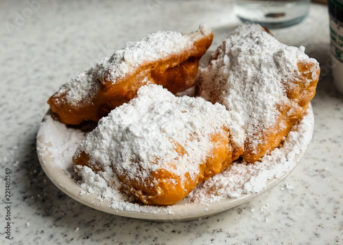 Fotografia Fresh beignets come out of the fryer, topped with powdered sugar, ready to eat