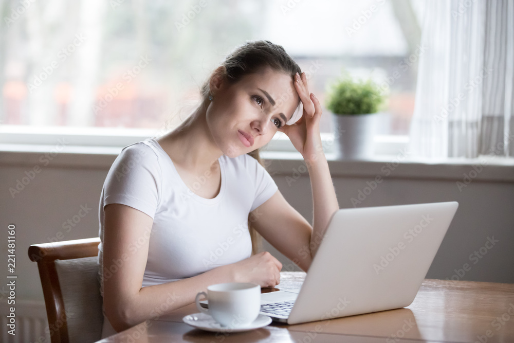 Unmotivated young woman frowning trying to remember important information, thoughtful girl sitting at laptop working looking for motivation, focused female thinking about problem solution Unmotivated young woman frowning trying to remember important information, thoughtful girl sitting at laptop working looking for motivation, focused female thinking about problem solution