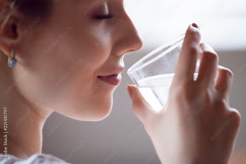 Close up of pretty female hold glass refreshing drinking pure mineral water in morning, thirsty woman feel dehydrated enjoying aqua having good habits, living healthy lifestyle taking care of herself Close up of pretty female hold glass refreshing drinking pure mineral water in morning, thirsty woman feel dehydrated enjoying aqua having good habits, living healthy lifestyle taking care of herself