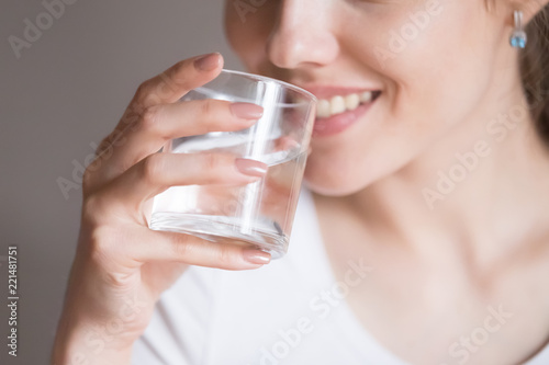 Canvas Print Close up of smiling woman feeling thirsty enjoying pure mineral water, dehydrated young female holding glass drinking aqua, girl taking care of own health