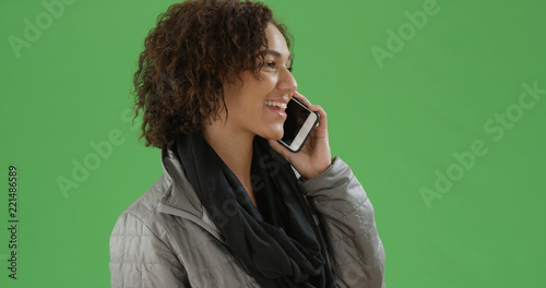 Young black millennial woman talking on smartphone on green screen