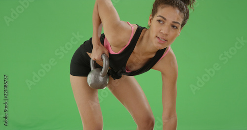 Young african American girl lifts a kettle bell on green screen