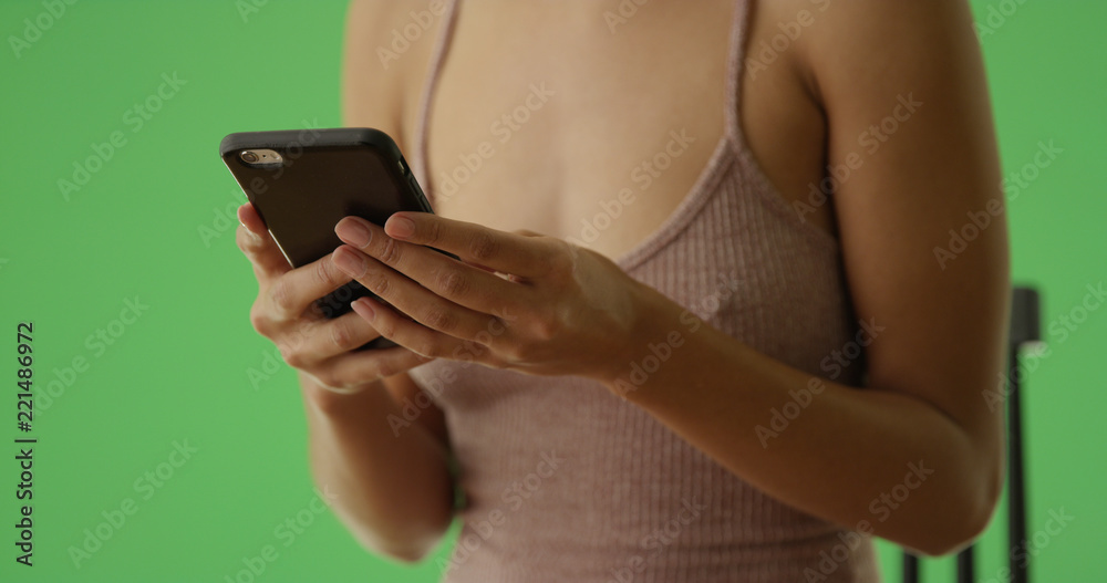 A millennial african American woman using her smartphone on green screen