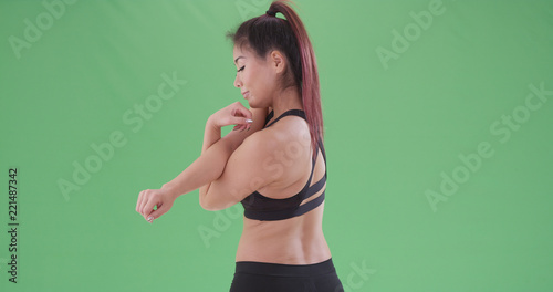 Athletic Asian woman stretching before workout on green screen
