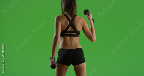 Hispanic girl lifting dumbbells with back to camera out on green screen