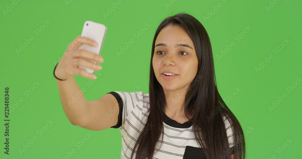Cute female teen takes a selfie with phone on green screen Cute female teen takes a selfie with phone on green screen