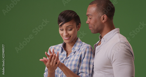 Black female with boyfriend admiring her engagement ring on green screen